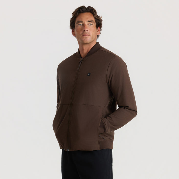 Man wearing tobacco brown Layover Bomber Jacket with full zip front and side pockets, styled on neutral background