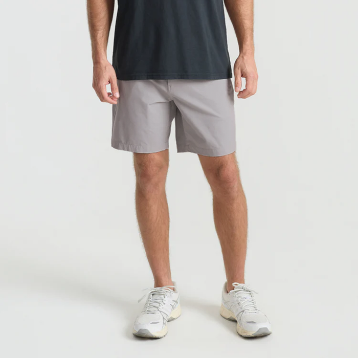 Roark adventure model showcasing versatile boardshorts while interacting with a calf, ideal for travel and outdoor activities.