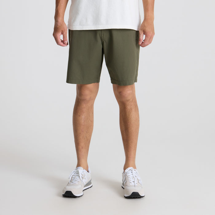 Adventurous person exploring outdoors wearing Bermuda shorts and walking shoes, in a natural setting that suggests travel and discovery.
