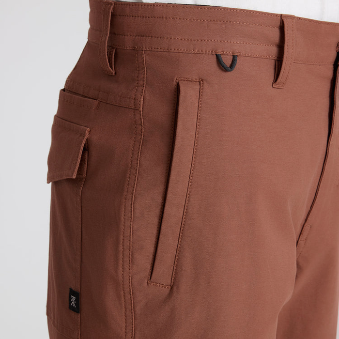 Layover Pro Traveler Shorts in red clay with cargo pockets and utility details, close-up of waistband and leg, flat lay view