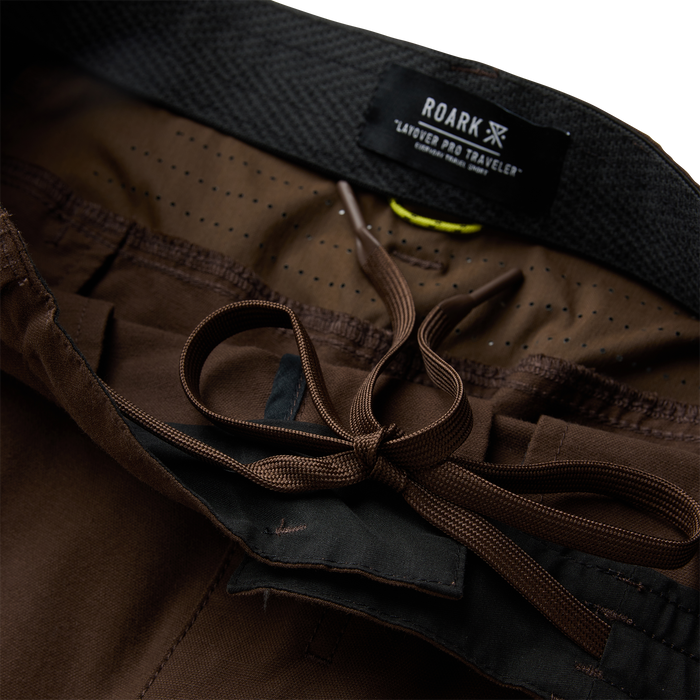 Roark Layover Pro Traveler shorts in tobacco brown with black waistband and brown drawstring, flat lay detail shot