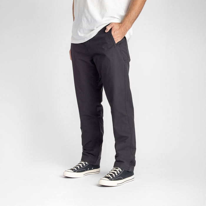 Model wearing Roark Layover Pro Black S325 pants in an outdoor setting, showcasing comfort and style for travel and adventure.