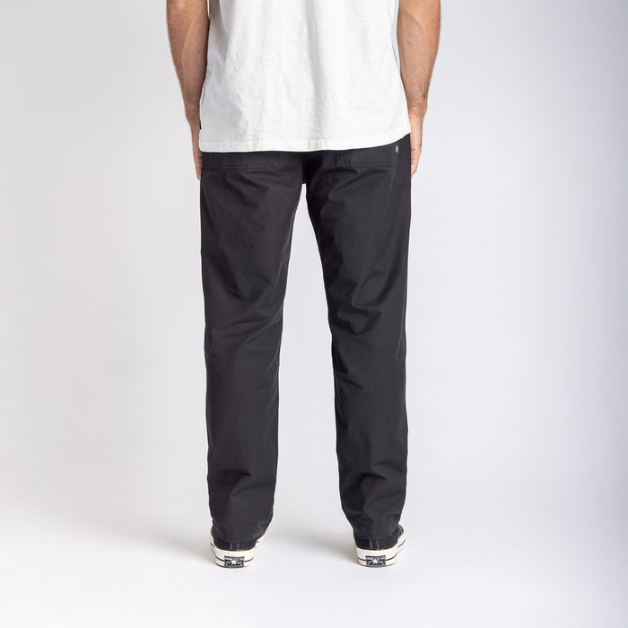 Man showcasing Roark's Layover Pro trousers in black while exploring urban landscape.