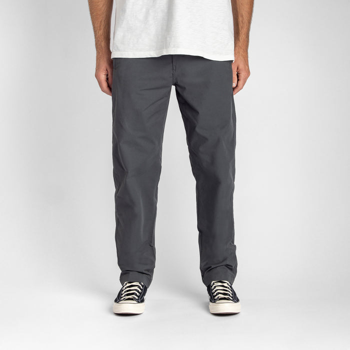 Man adventurously exploring through rugged terrain wearing Roark's Layover Pro Charcoal pants.