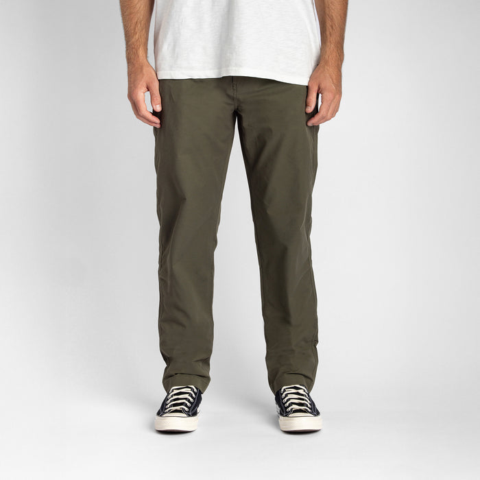 Adventurous traveler wearing the Roark Layover Pro Military pants exploring a rugged trail surrounded by natural scenery