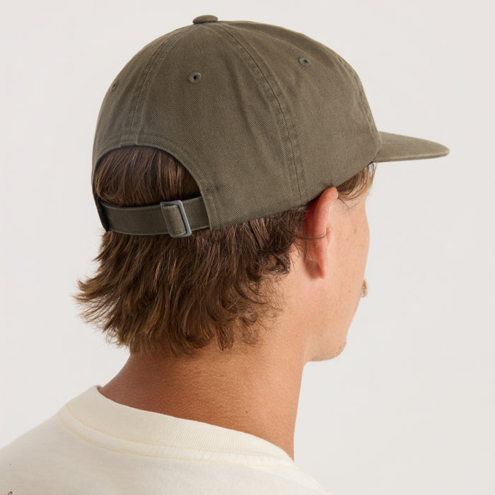 Olive green washed cotton baseball cap with adjustable strapback closure, shown on male model from side view wearing cream shirt