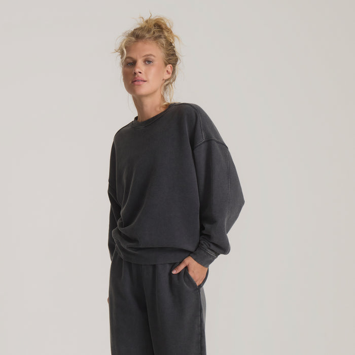 Woman wearing charcoal vintage black fleece sweatshirt with crew neckline and relaxed fit, standing against neutral background