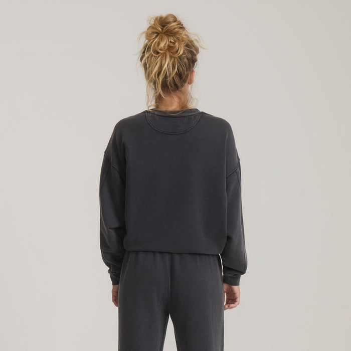 Made To Fade Fleece Hoodie in vintage black worn by model, shown from back view with blonde hair in bun
