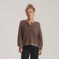 Taupe ribbed henley sweater with long sleeves and button placket worn by model with black jeans