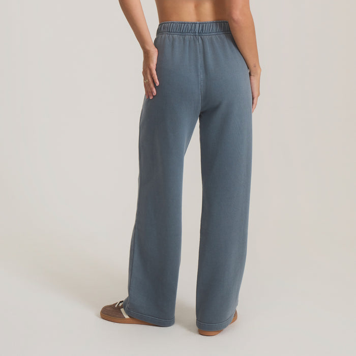Made To Fade Pants in slate blue, wide-leg fit with elastic waistband, shown from back on model wearing brown sandals