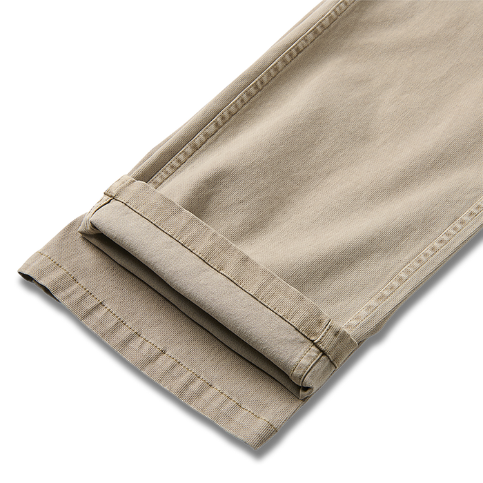 Sturdy khaki cargo pants with button details and multiple pockets, perfect for adventure and travel, from Roark’s collection.
