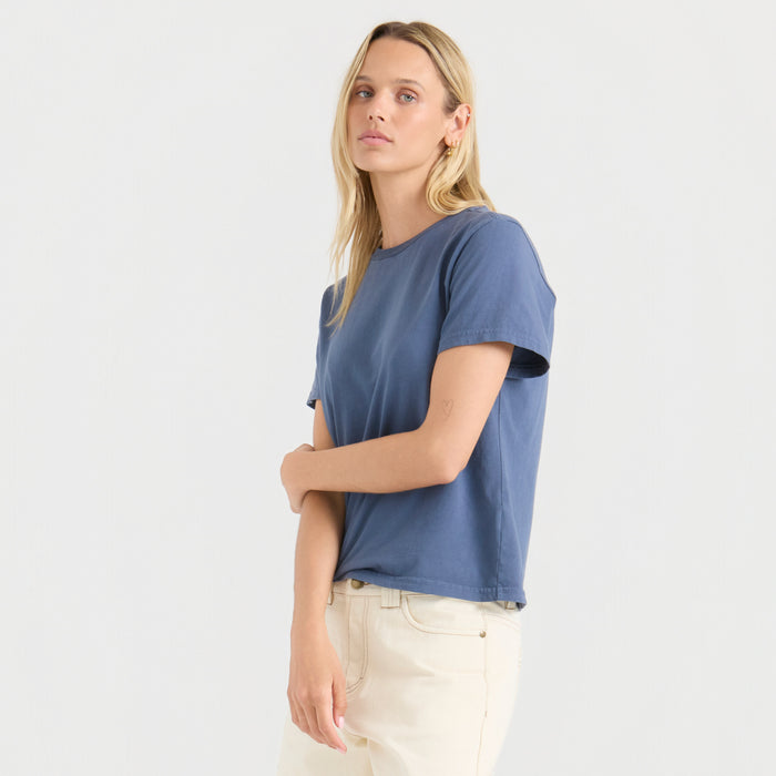 Made To Fade Premium Tee in Neptune blue worn by model with white pants, shown from side angle
