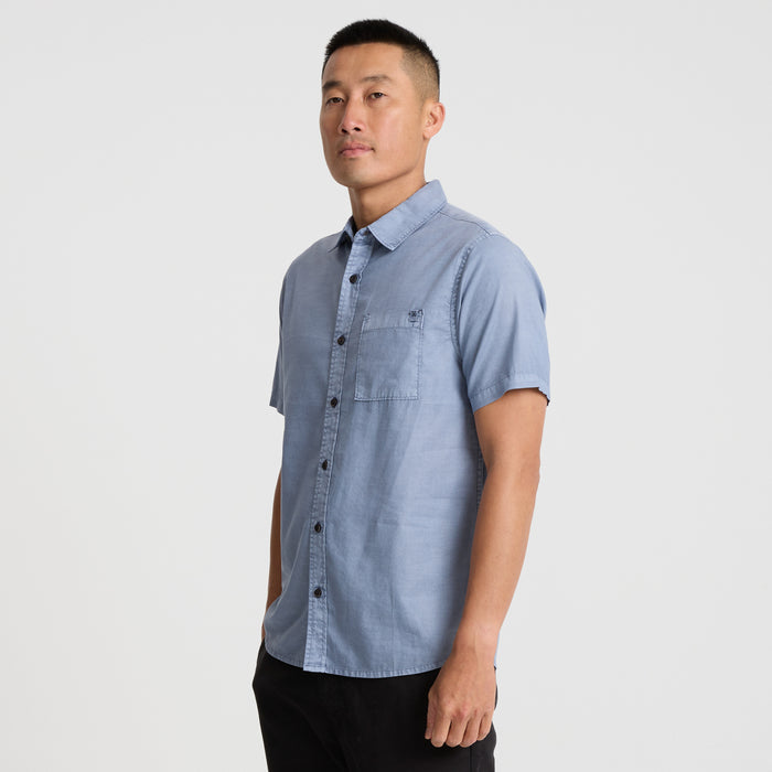 Close-up view of an adventure-ready Roark dress shirt featuring a sturdy collar, secure buttons, and textured pocket detail, ideal for travel and outdoor activities.