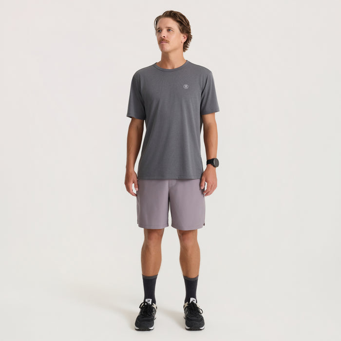 Charcoal short sleeve tee with small chest logo worn by male model with light purple shorts and black sneakers