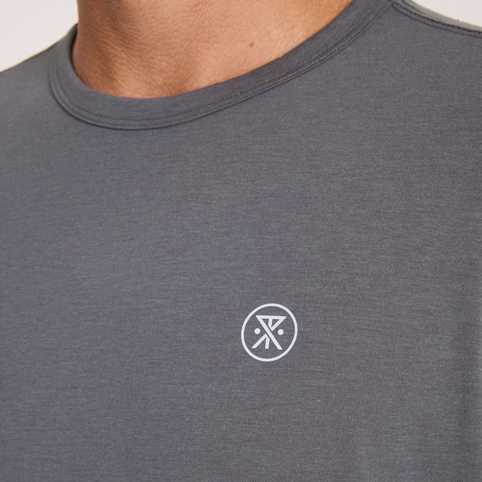 Charcoal gray short sleeve crew neck tee with small white circular logo on chest, worn by model
