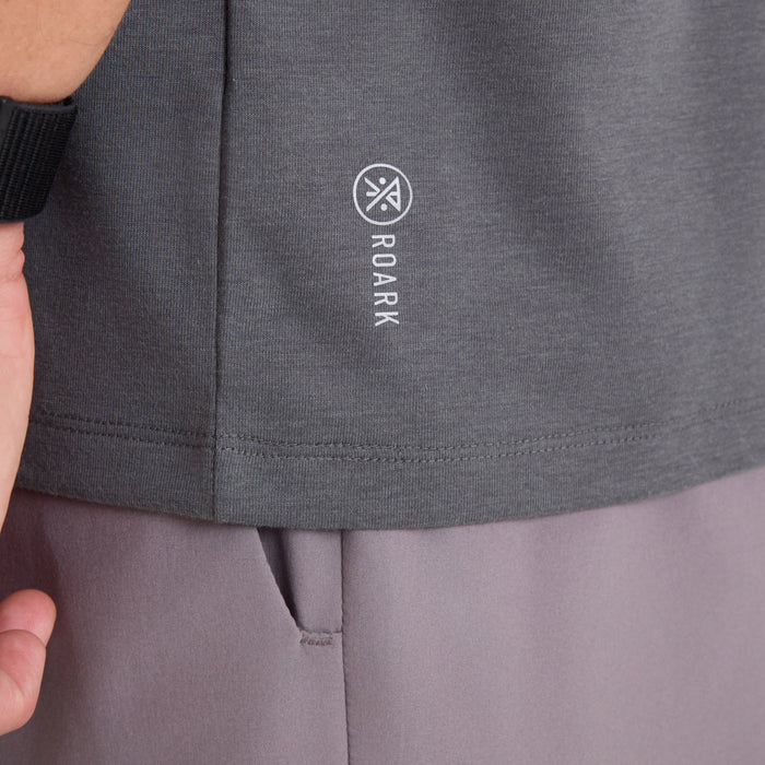 Charcoal short sleeve tee with Roark logo and text printed on chest, worn on model with mauve pants