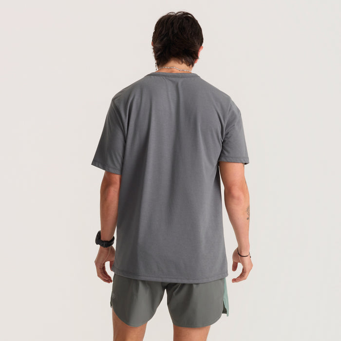 Active man wearing a grey shirt and Bermuda shorts on a brisk run in an outdoor setting, embodying Roark’s adventure and travel spirit.