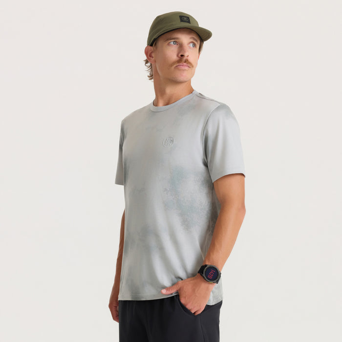 Mathis Active Allover short sleeve tee in grey worn by man with olive cap and digital watch on neutral background