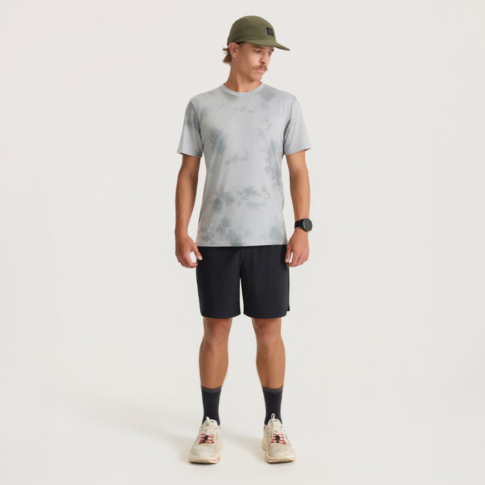 Man wearing grey tie-dye Mathis Active short sleeve tee with black shorts and olive baseball cap in full-length lifestyle shot