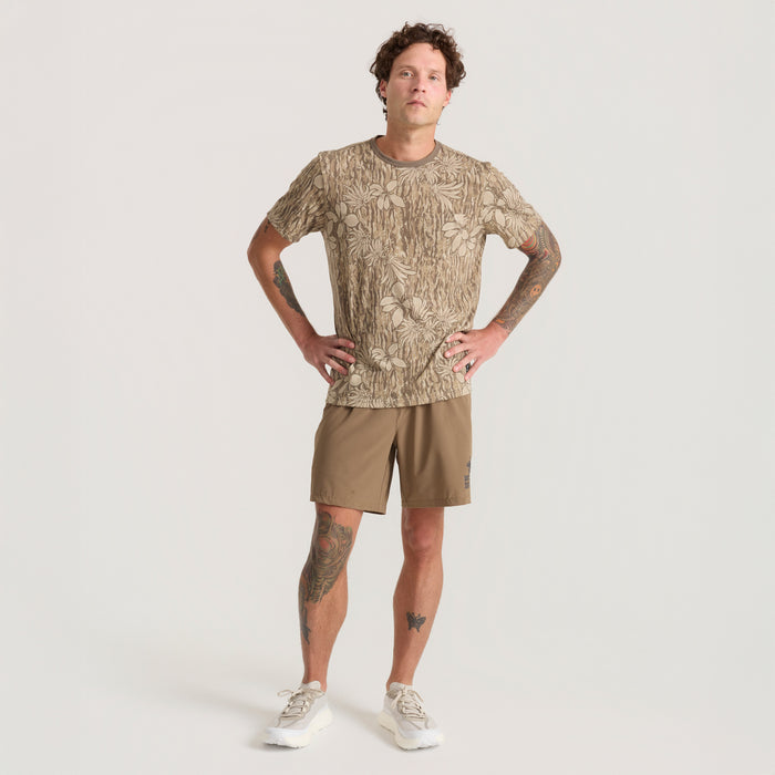 Active man wearing a brown Roark active shirt paired with boardshorts, ready for an adventurous outing.