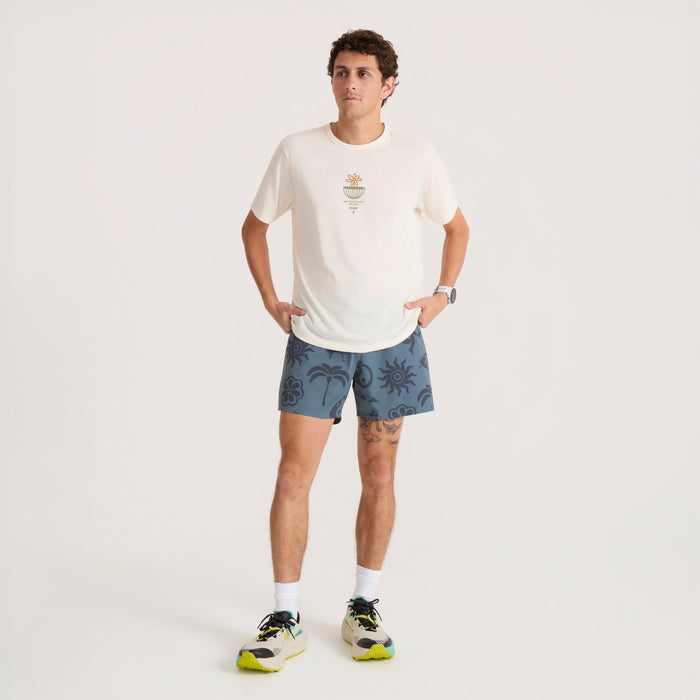 Mathis Active Graphic Short Sleeve Tee in unbleached worn by man with blue patterned shorts in lifestyle pose