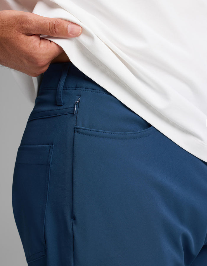 A person in Cozy Earth's Men's Everywhere Pant - Relaxed Fit reveals the waistband and pocket details by lifting their white shirt.|Color:Obsidian