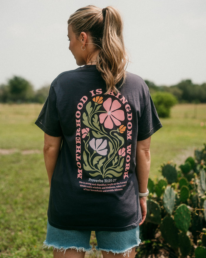 Person wearing a black t-shirt with floral design and text in an outdoor setting