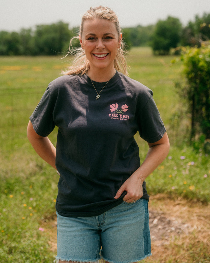 Woman wearing a black t-shirt with a logo in a field
