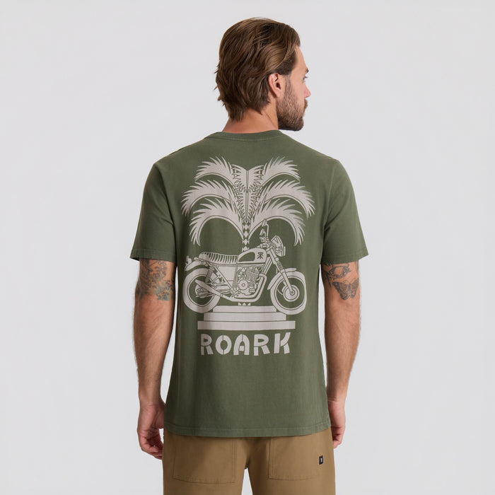 Active shirt by Roark styled for adventure amidst lush palm trees, capturing the essence of tropical exploration.