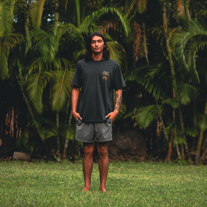 Model dressed in active summer attire featuring a Moto Palm Premium Tee and boardshorts, ideal for adventure and travel.