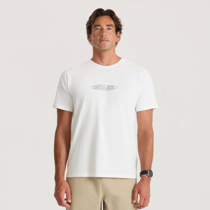 White Moto Premium Tee with small oval logo on chest, worn by man with beige shorts on neutral background