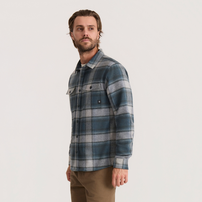 Nordsman 2.0 long sleeve flannel in dark slate plaid worn by male model with brown pants