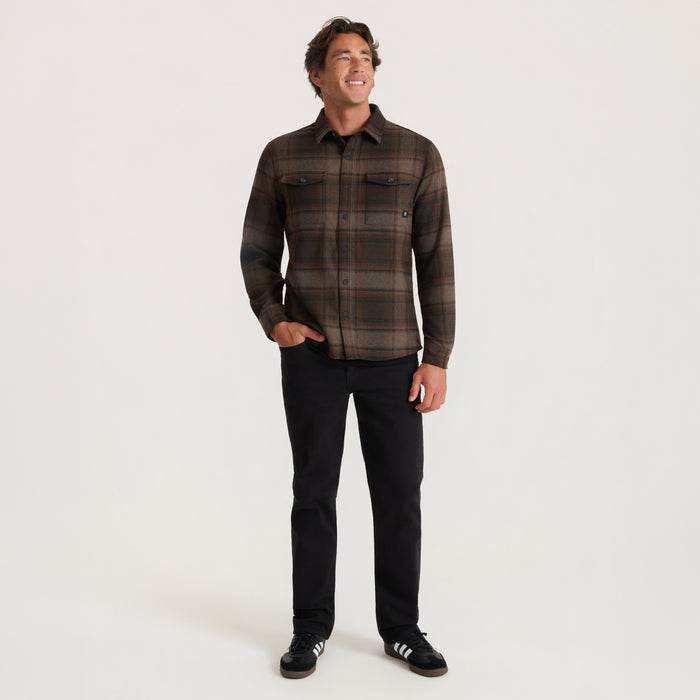 Man wearing brown plaid Nordsman 2.0 long sleeve flannel shirt with black pants, shown in full-body front view