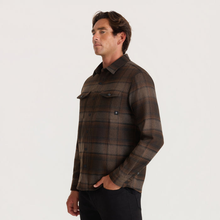 Brown plaid flannel shirt with chest pockets worn by male model in side profile against neutral background