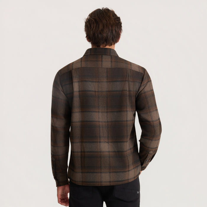Man wearing brown and rust plaid flannel shirt with long sleeves, shown from back view against neutral background