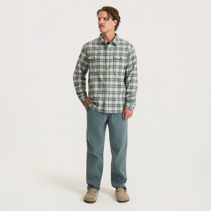 Man wearing Nordsman 2.0 sand plaid flannel shirt with blue-green jeans and beige suede boots, full-length front view