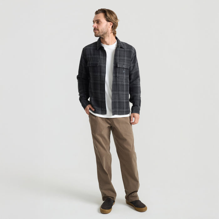 Close-up of a durable pocket detail on a black outdoor adventure garment by Roark, highlighting robust material and stitching for travel durability.