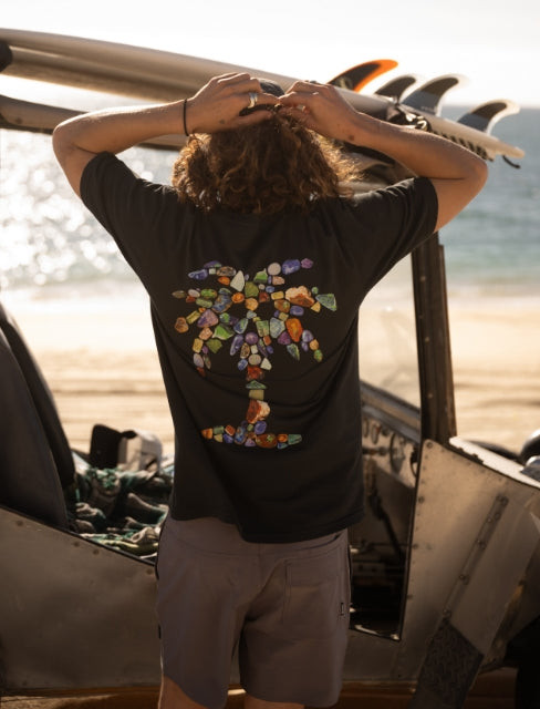 Active shirt on a beach with palm trees, highlighting Roark's adventure essentials for tropical destinations.