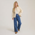 Cream Open Roads Cardigan worn by model with blue jeans and brown boots on neutral background