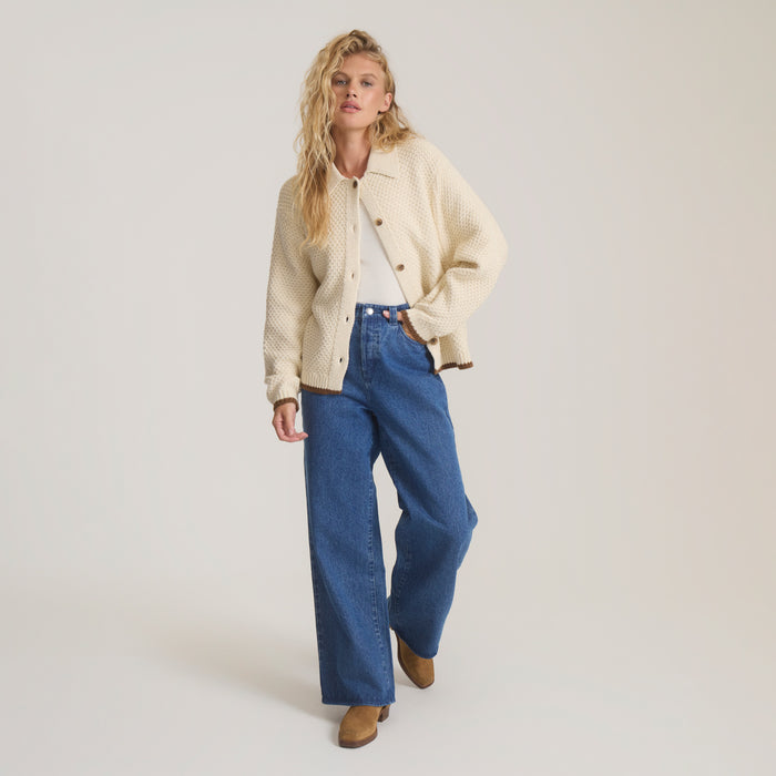 Cream Open Roads Cardigan worn by model with blue jeans and brown boots on neutral background