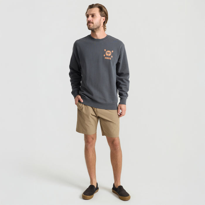 Model wearing Roark long-sleeved active shirt and boardshorts, styled for adventure and travel, in a dynamic outdoor setting