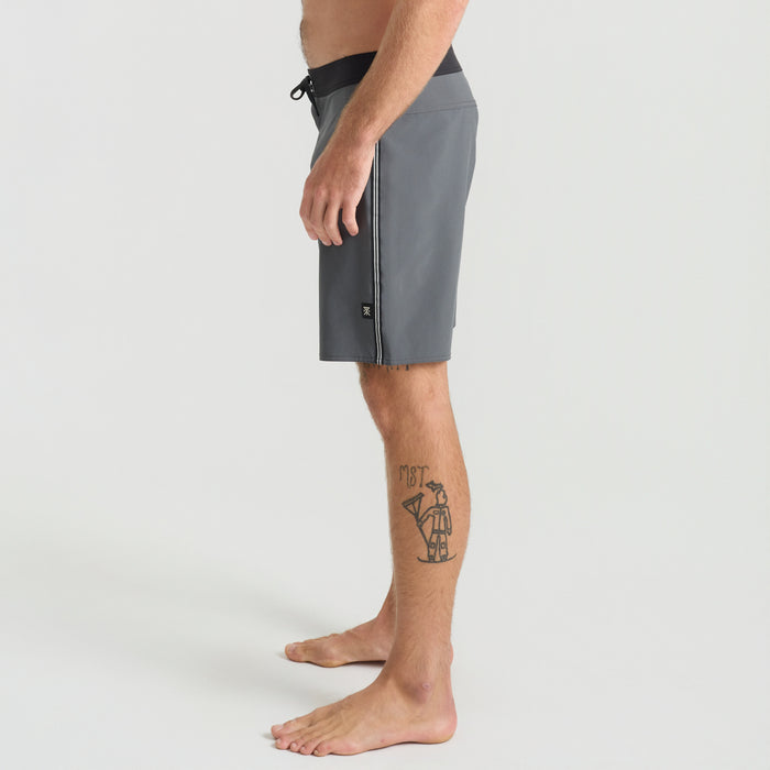 Man in boardshorts enjoying a recreational day by the coastal shore, embodying the adventurous spirit of Roark’s outdoor lifestyle.