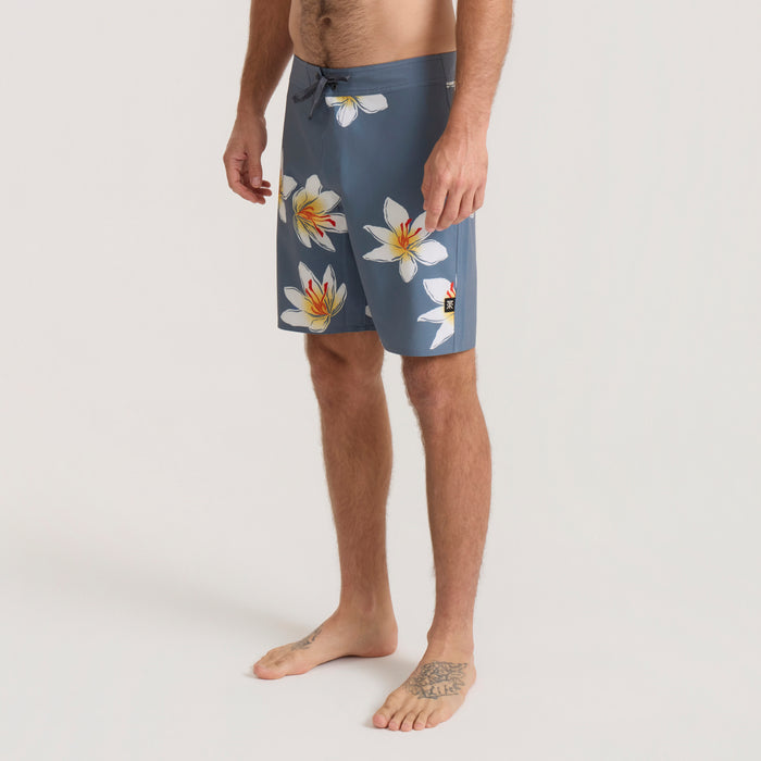 Slate blue Passage Boardshorts with white and yellow floral print, worn by man on neutral background