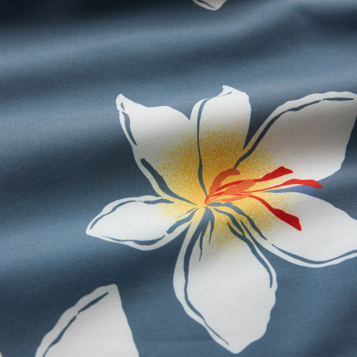 Slate blue boardshorts fabric detail showing white and yellow floral print with red flower stamen design