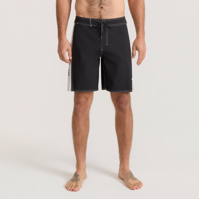 Black and white Passage Panel Boardshorts with drawstring waistband worn by man standing barefoot against neutral background