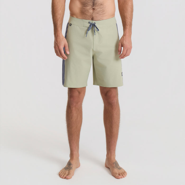 Vacationer relaxing on the coast wearing Roark boardshorts, embodying the adventure and travel spirit.