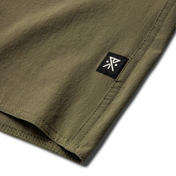 Man adventurously dressed in an active shirt with pocket and bermuda shorts, embodying Roark's spirit of travel and outdoor exploration.