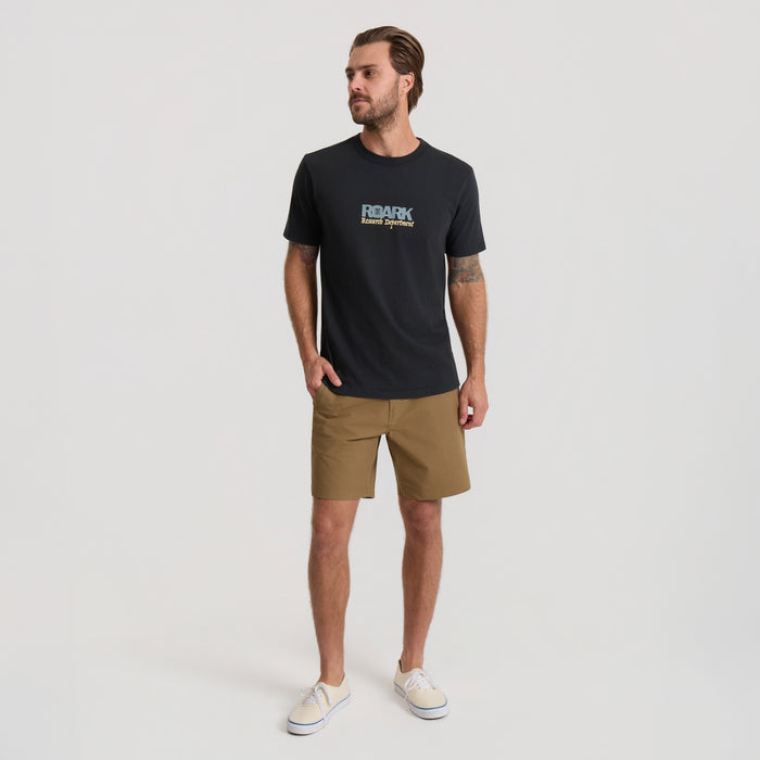 Man outfitted in versatile Roark active shorts and shirt, ideal for outdoor adventures and travel.