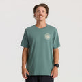 Sage green short sleeve tee with small circular logo graphic on chest, worn by man against plain background