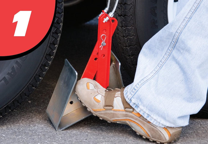 Step 1 – foot pressing ONESTEP trailer wheel chock 84-00-4840 into position between dual tires | United RV Parts